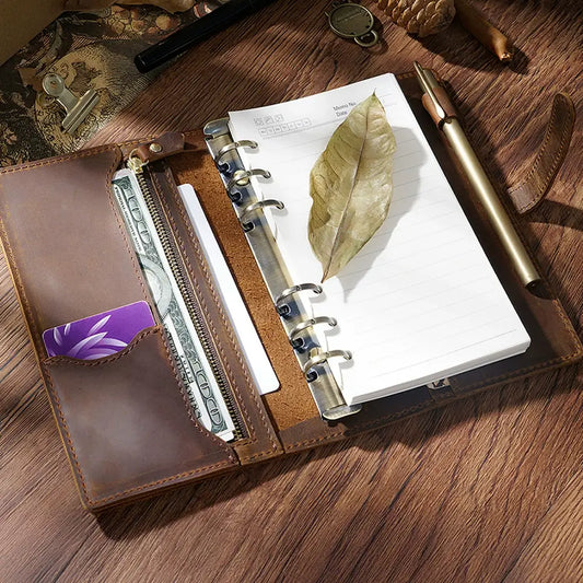 Open leather wallet with money and planner on a wooden surface