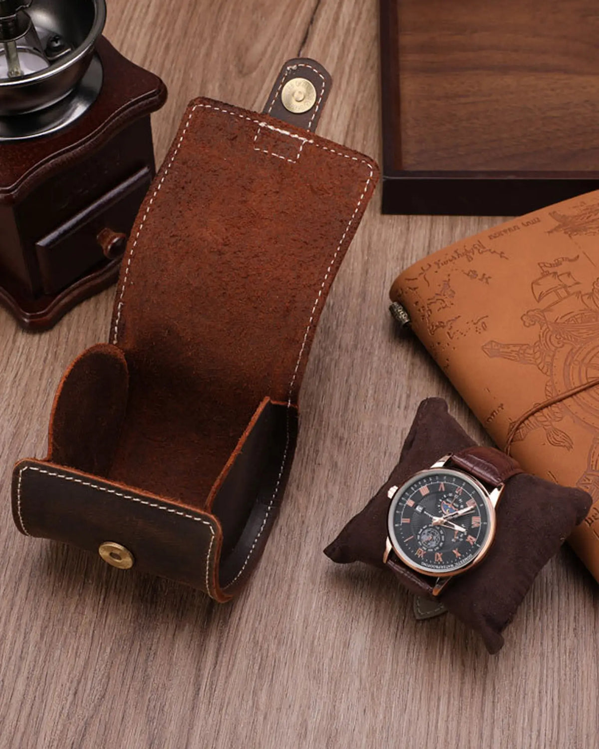 Open single-watch roll beside a watch and journal on a table