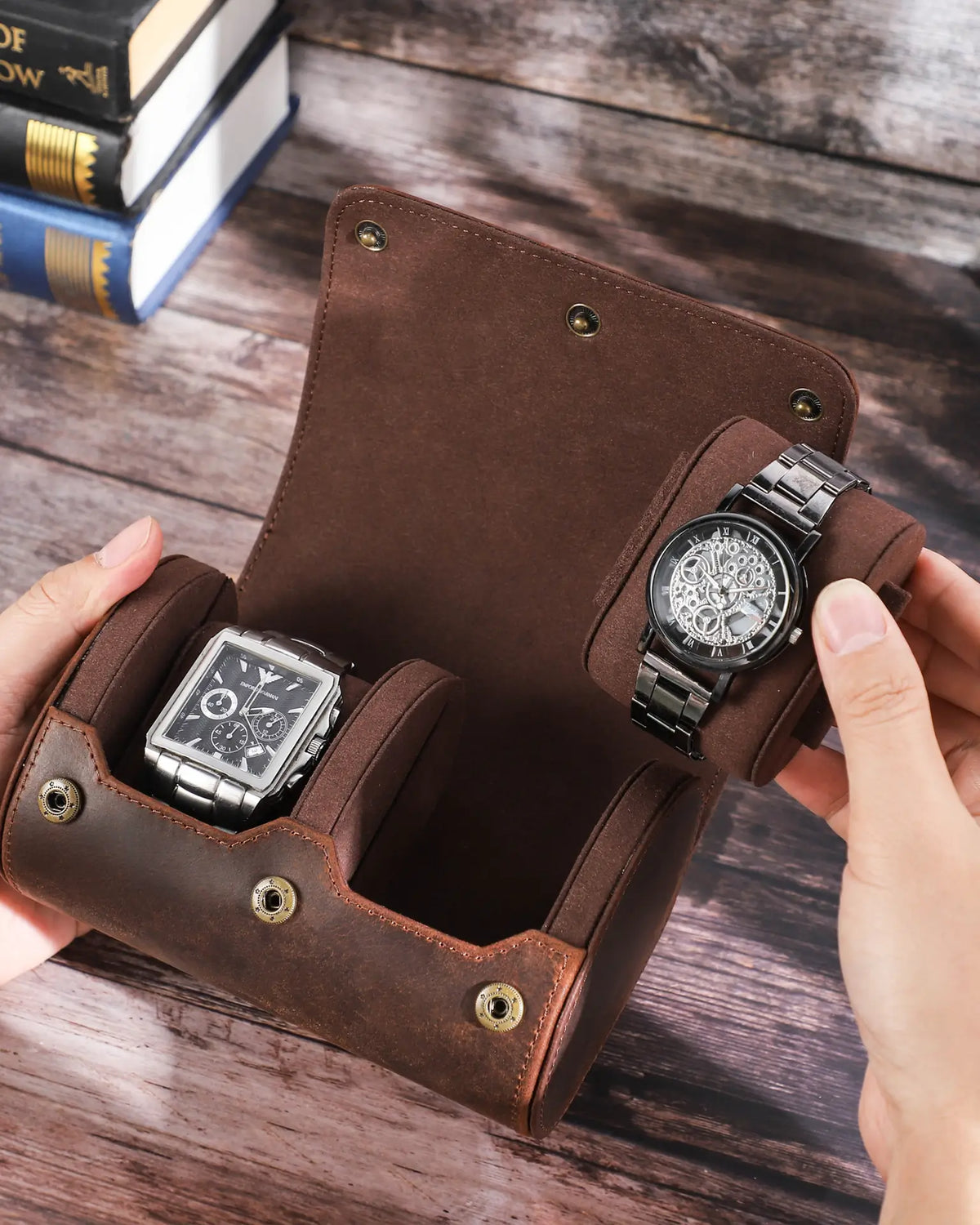 Hand placing a watch into a roll beside a square-face watch