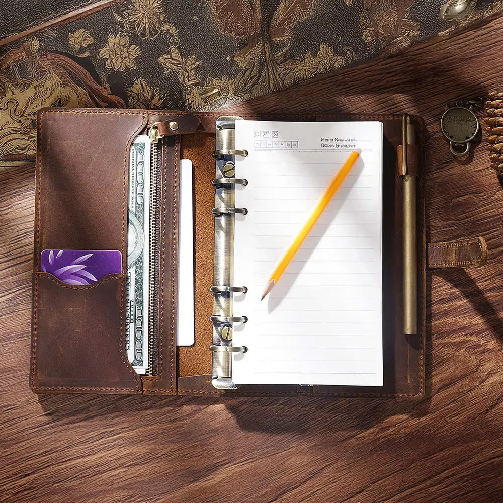 Brown leather planner with pen and pencil on a wooden surface