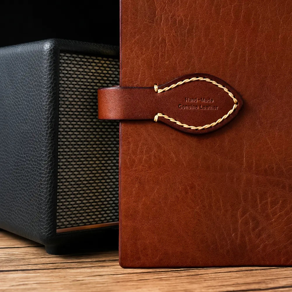 Brown leather-bound book with a black textured object on a wooden surface