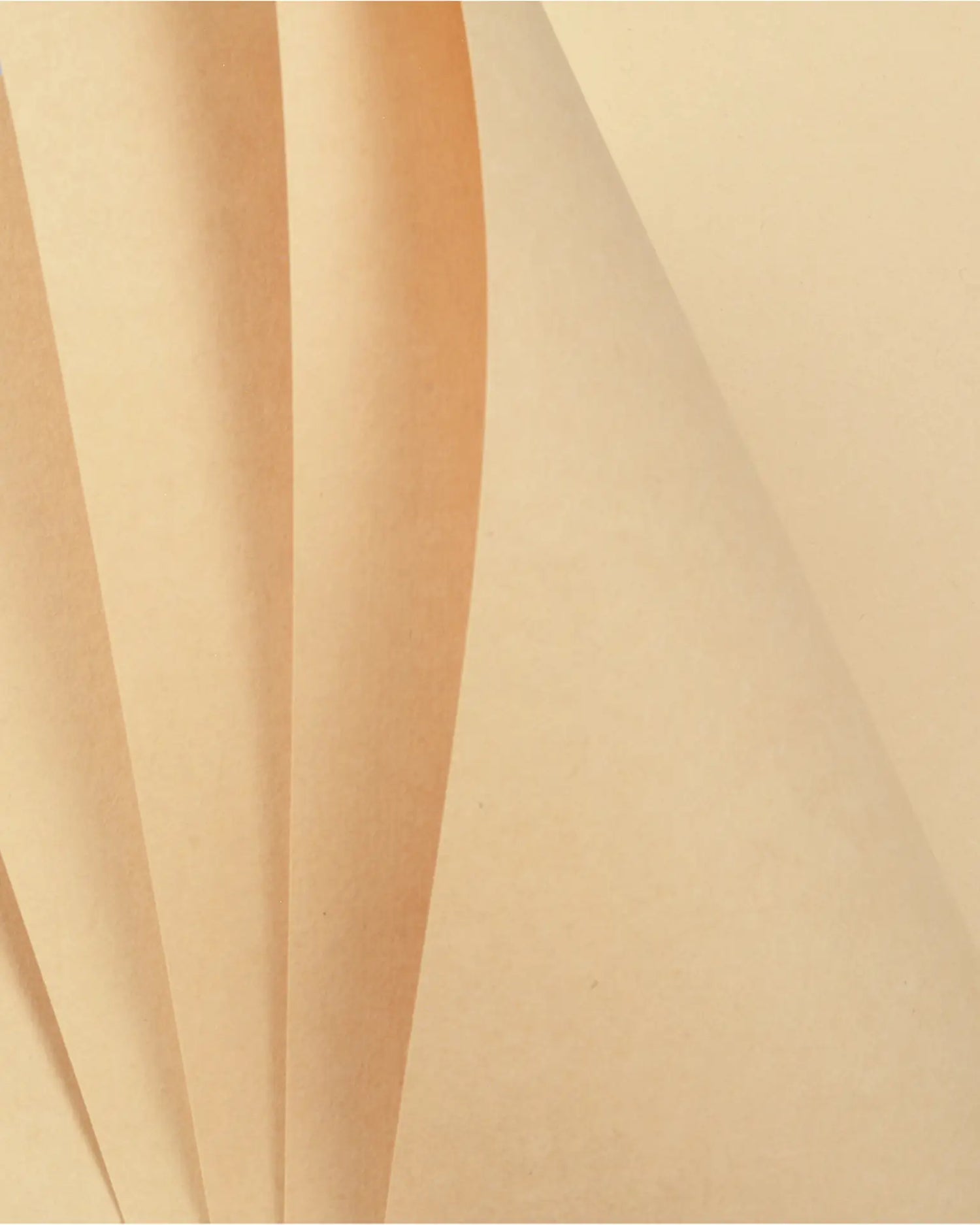 A close-up of folded beige paper or cardstock layers with soft shadows and a warm cream tone.