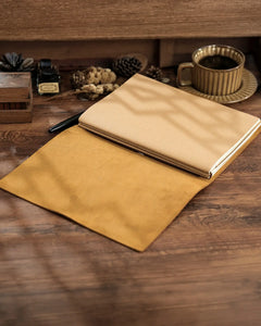 Open Cognac B5 refillable leather journal with notebook inserts on a wooden desk
