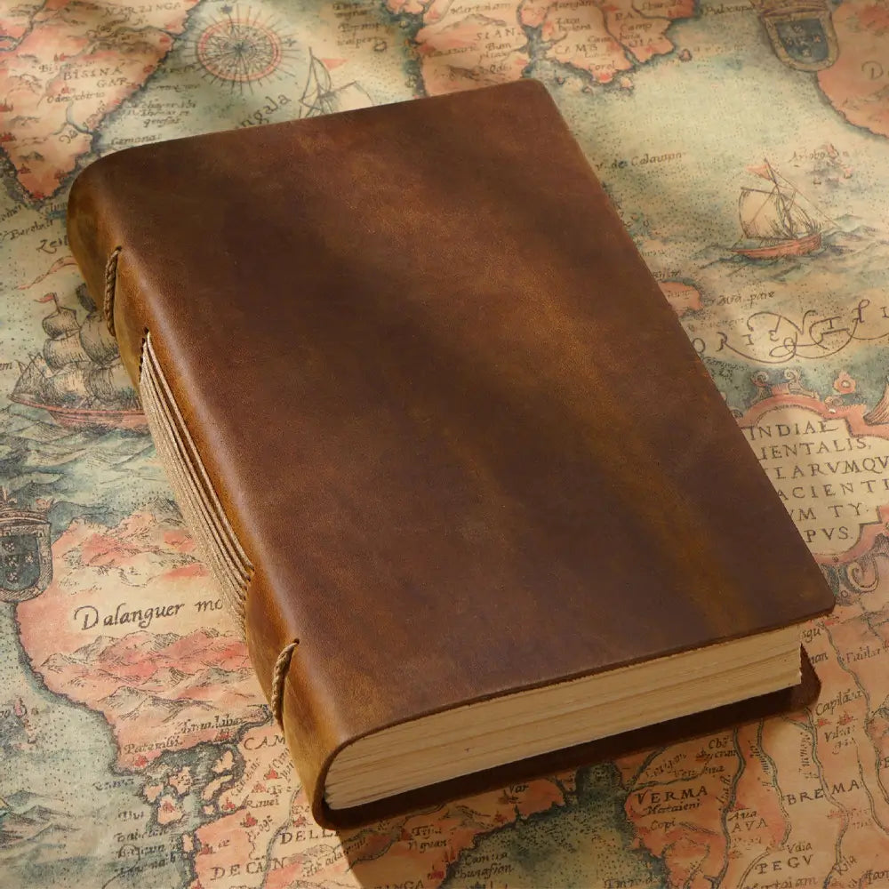 The brown vintage leather diary is on an old map.