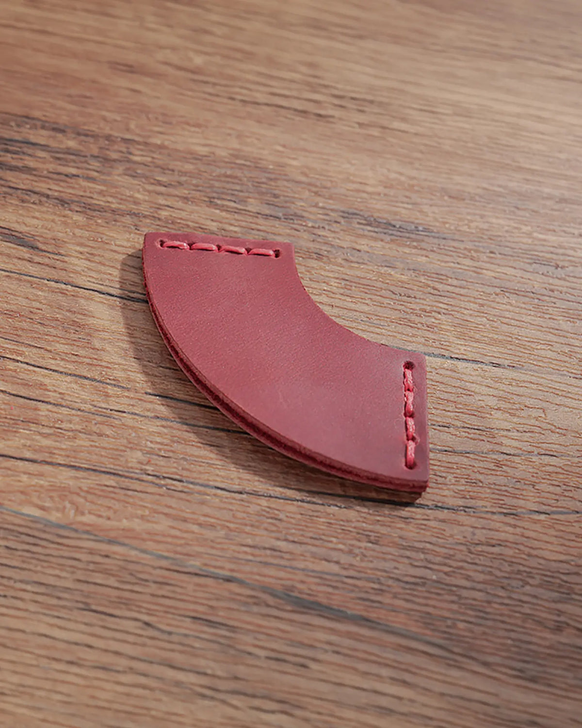 Crimson red leather corner bookmark with fan-shaped profile and stitched ends