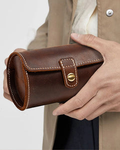 Person holding a closed dark brown double-watch roll