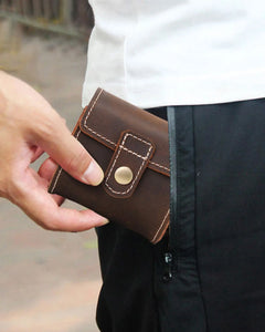 Person slipping a closed single-watch roll into a trouser pocket