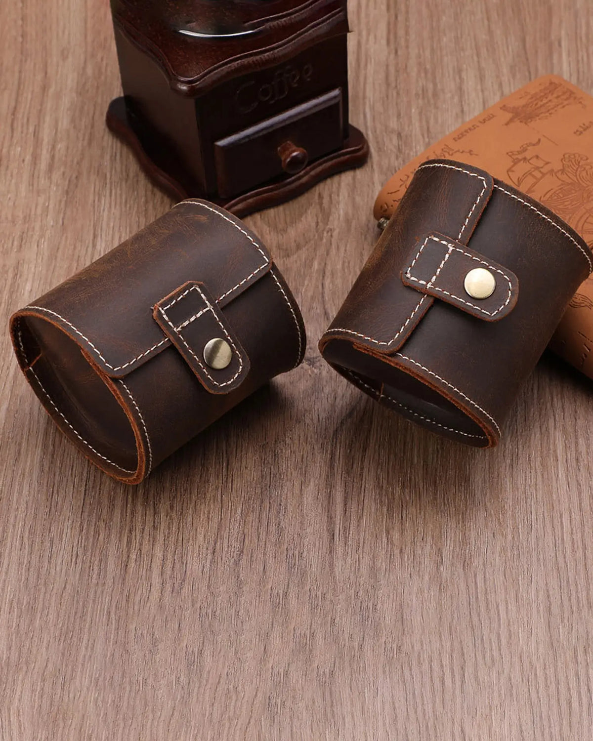 Two closed dark brown single-watch rolls on a wooden table