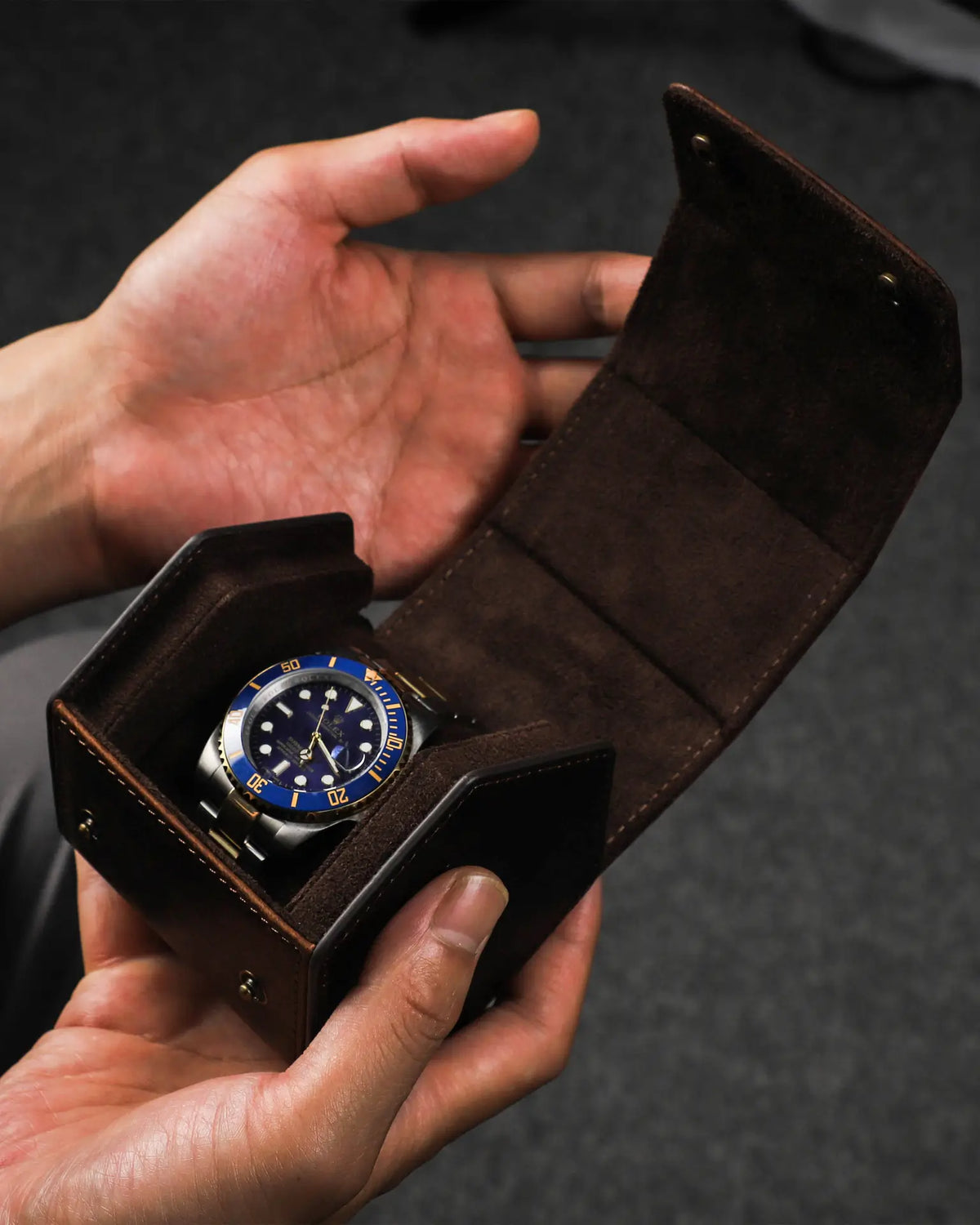 Hands holding an open hex watch box with a watch inside