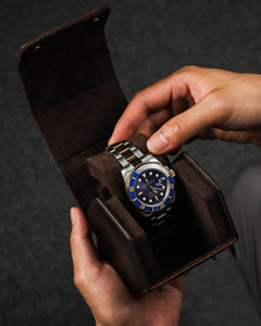 Hands lifting a watch from an open single-watch box