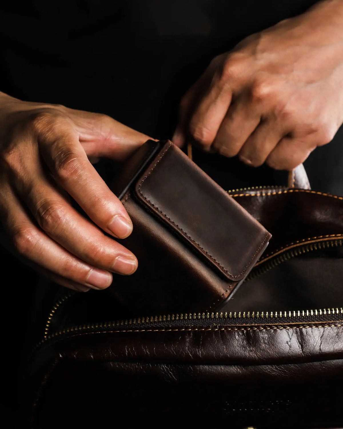 Hand packing a closed single-watch box into a travel bag