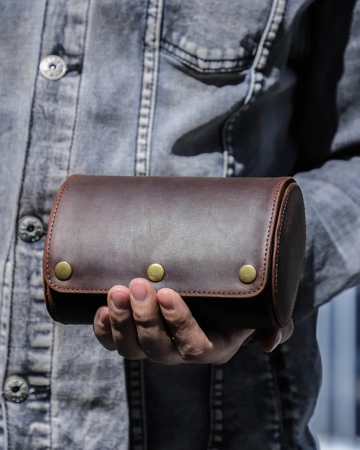 Person holding a closed dark brown double-watch roll