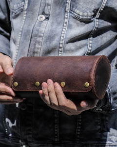 Person holding a closed dark brown three-watch roll