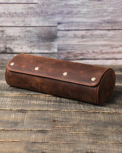 Closed dark brown three-watch roll on a rustic table