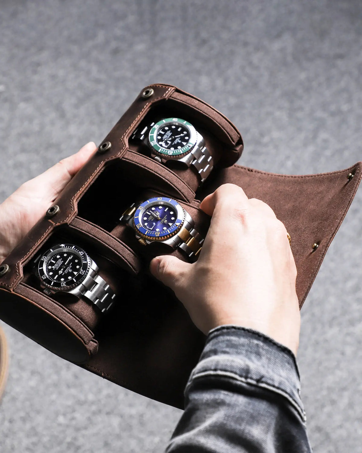 Hands placing a watch into an open three-watch roll