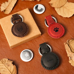 Four AirTag case on a brown leather surface with leaves.