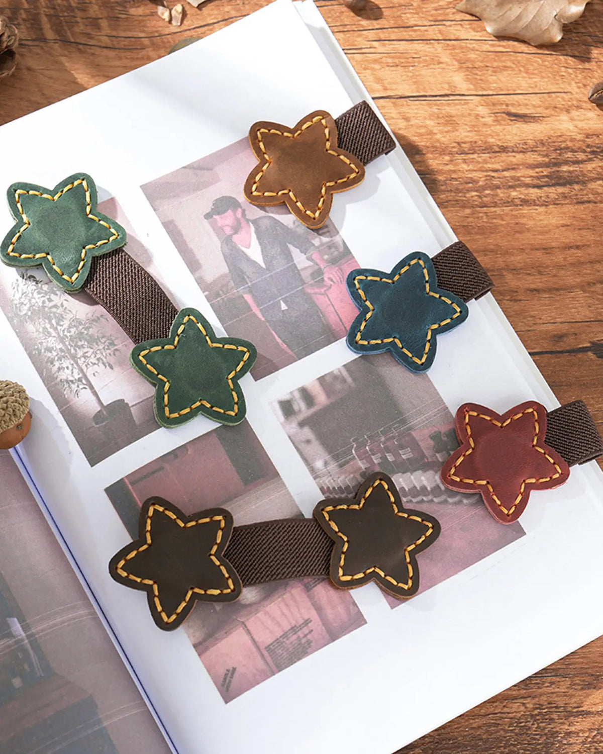 Star leather magnetic bookmarks with elastic pen loops displayed in five colors on an open book