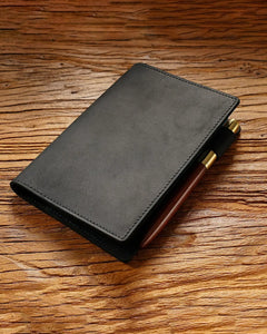 Black A6 leather writing folio with a pen beside the cover