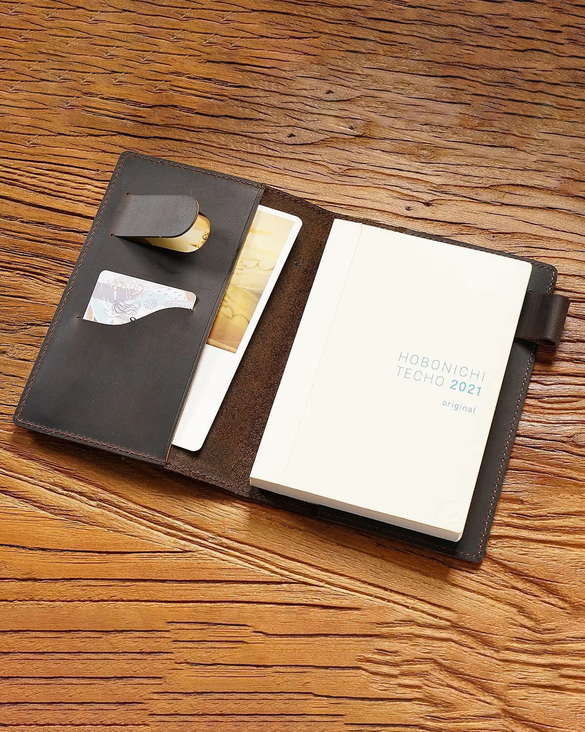 Open A6 leather writing folio holding a bound notebook with pockets and pen loop