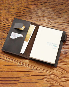 Open A6 leather writing folio holding a bound notebook with pockets and pen loop