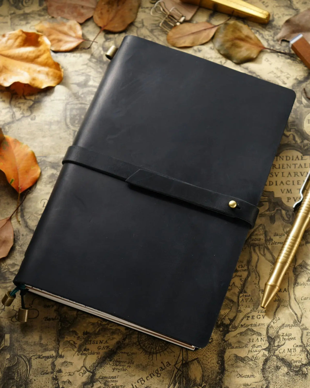 Black A5 leather traveler’s notebook with wrap strap on a writing desk