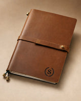 Cognac A5 leather traveler’s notebook with wrap strap and monogram example