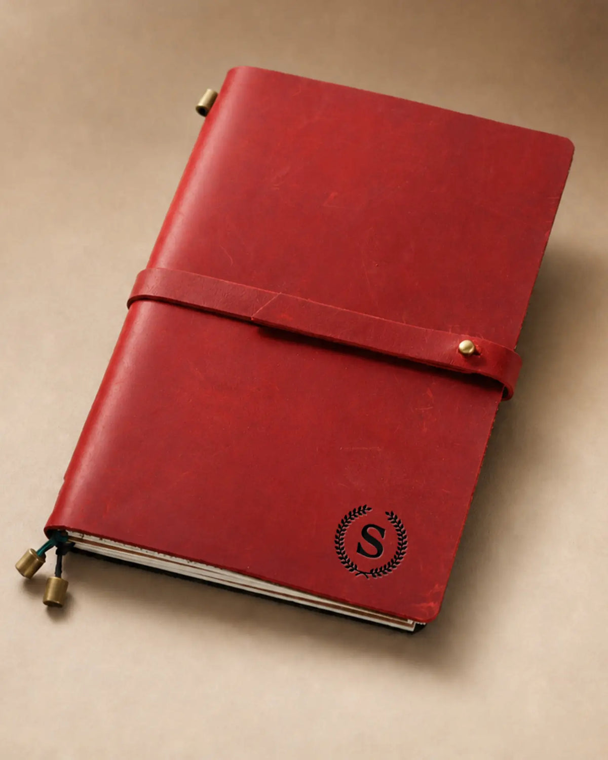 Crimson A5 leather traveler’s notebook with wrap strap and monogram example