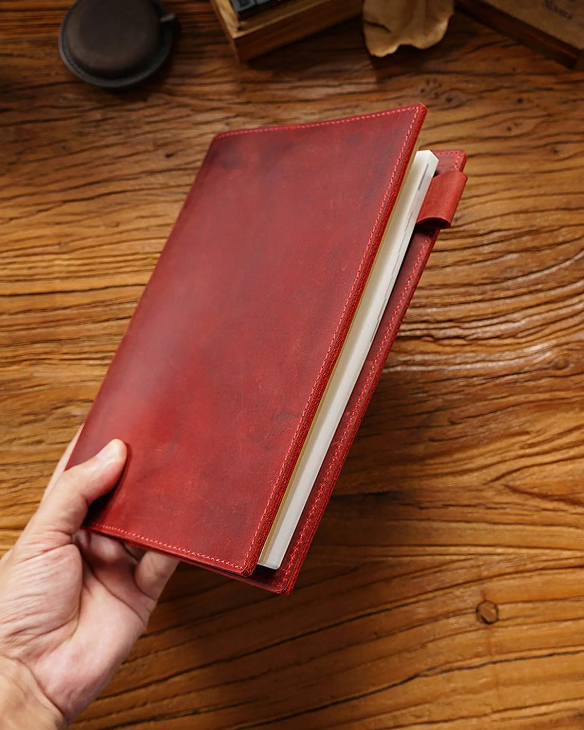 Crimson A5 leather writing folio holding a bound notebook beside the pen loop