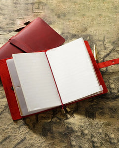 Open Crimson Journey Wrap notebook showing lined pages and an elastic holding cord
