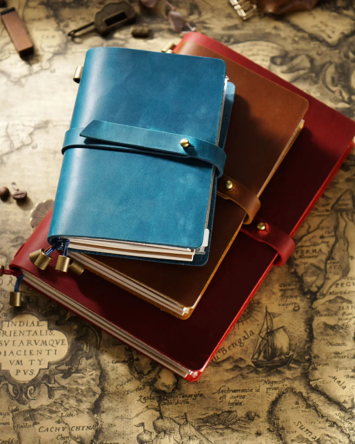 Teal Blue and warm-tone Journey Wrap notebooks stacked in different sizes