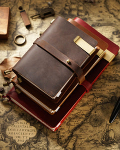 Espresso, Cognac, and Crimson Journey Wrap notebooks shown with pen clips