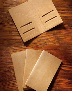 Three notebook inserts beside an open kraft card holder with slots