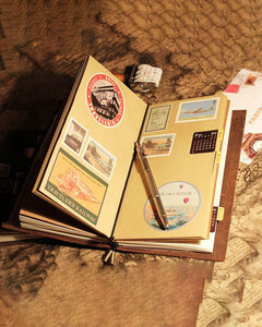 Open Journey Wrap notebook decorated with travel stickers and keepsakes