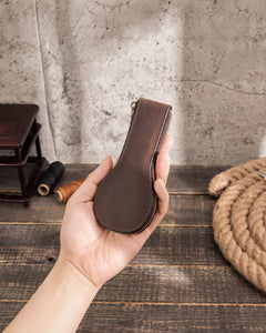 Closed Espresso leather watch case held in one hand, showing its slim profile and zipper.