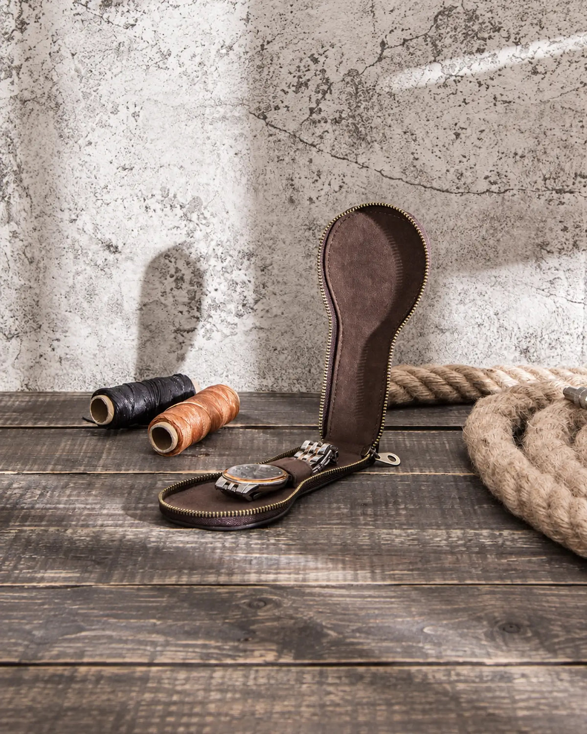 Open single watch case on a wooden worktable, showing the interior and watch strap holder.