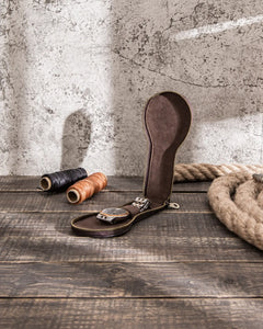 Open single watch case on a wooden worktable, showing the interior and watch strap holder.