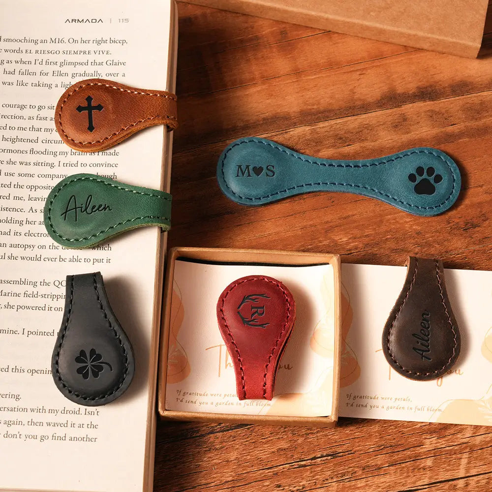 Collection of leather bookmarks with various designs on a wooden surface.