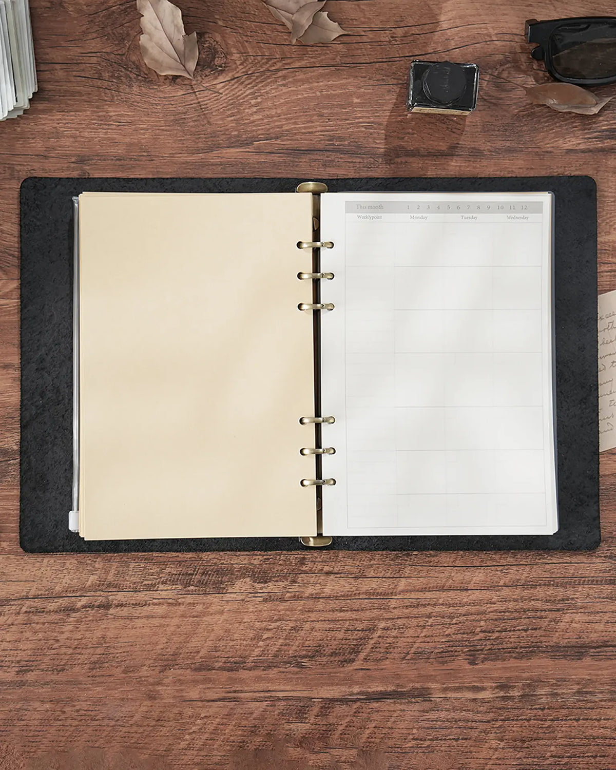 Open Black A4 leather journal showing the four-ring binder and loose-leaf pages