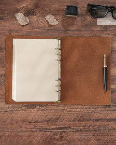 Open Cognac A4 leather journal showing the four-ring binder and loose-leaf pages