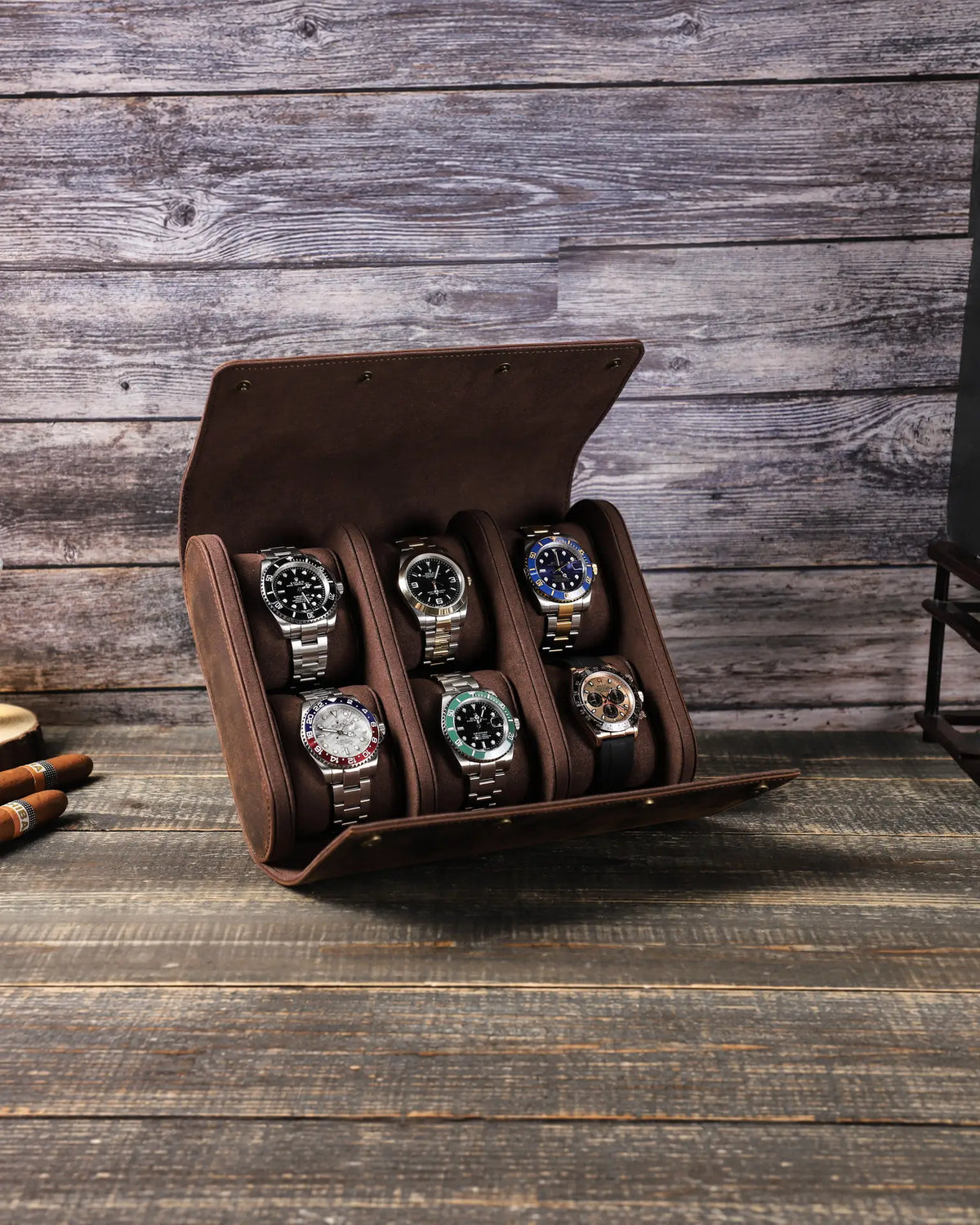 Front view of the open six-watch case, showing two rows of three watches on a wooden table.