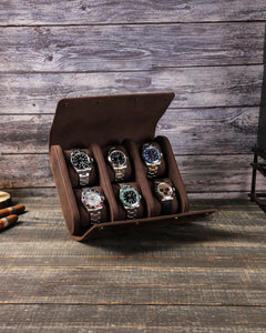 Front view of the open six-watch case, showing two rows of three watches on a wooden table.