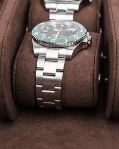 Close-up of a metal-bracelet watch on a removable brown cushion inside the six-watch case.