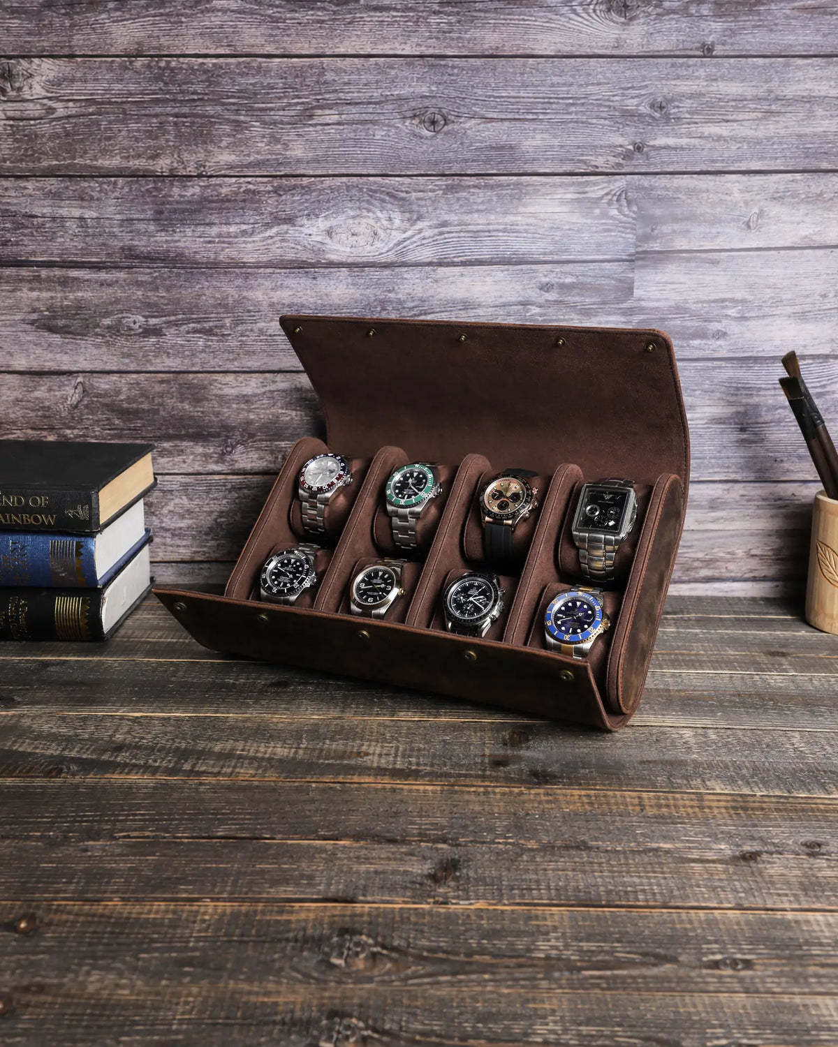 Brown eight-watch case open on a wooden table with two rows of four watches.