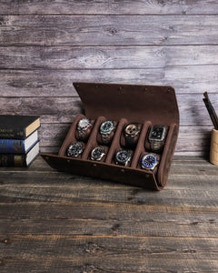 Brown eight-watch case open on a wooden table with two rows of four watches.