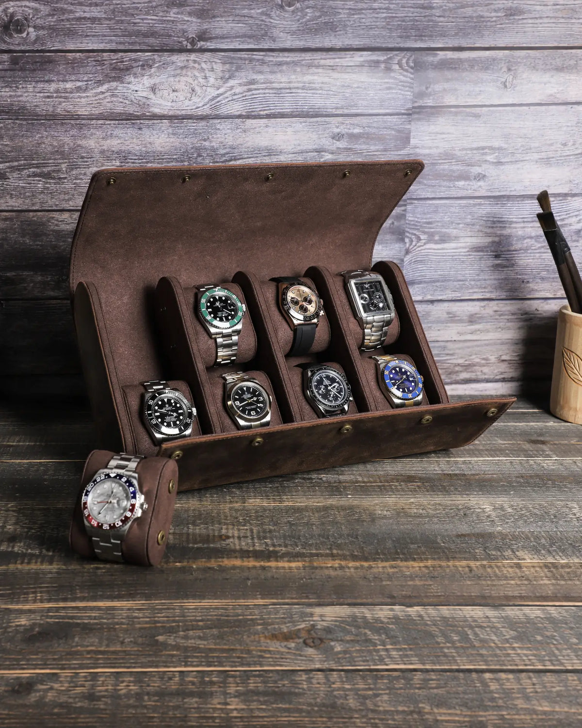 Espresso eight-watch case open on a wooden table with one watch cushion removed beside it.