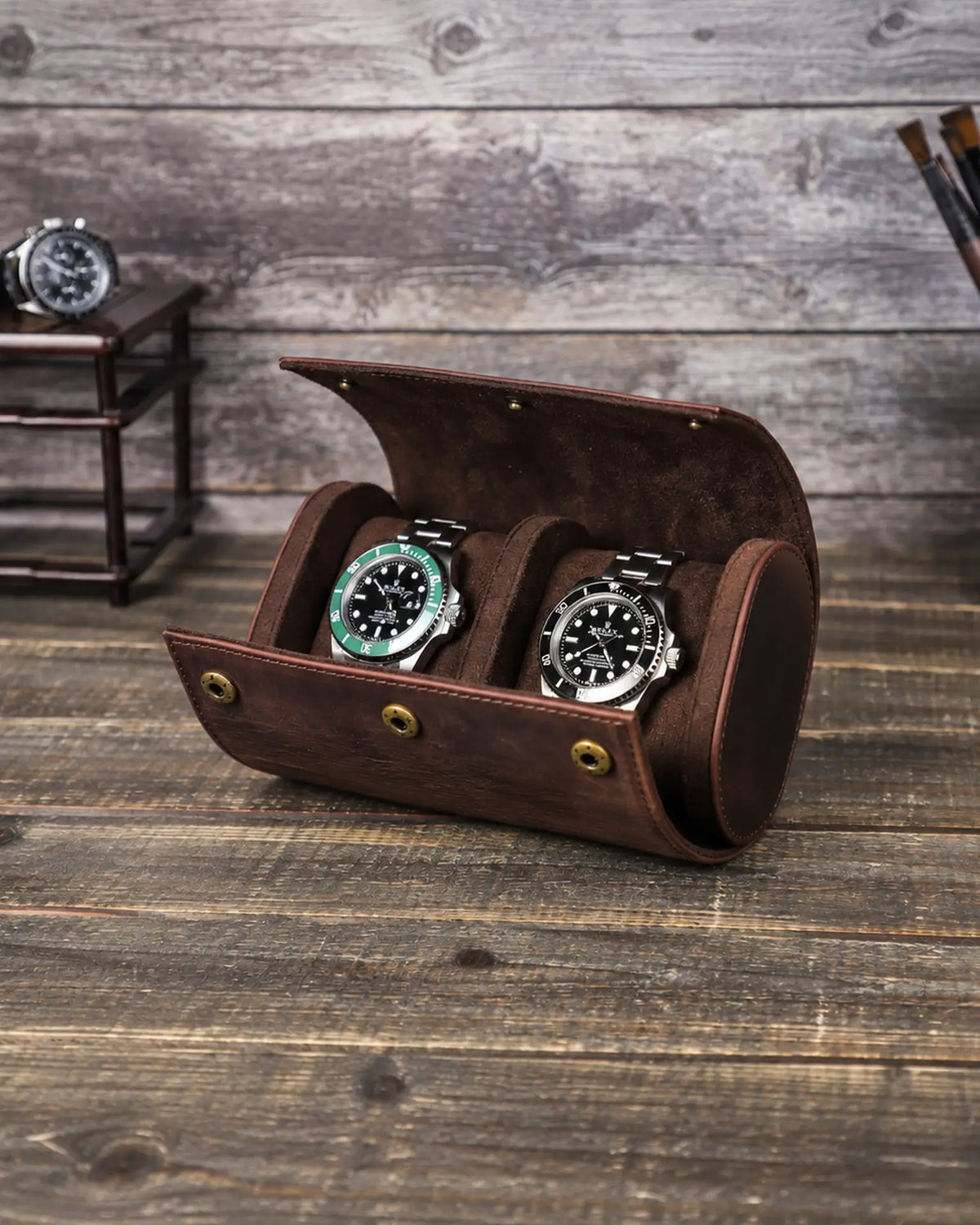 Brown double watch roll open on a wooden table, showing two watch cushions and the central divider.