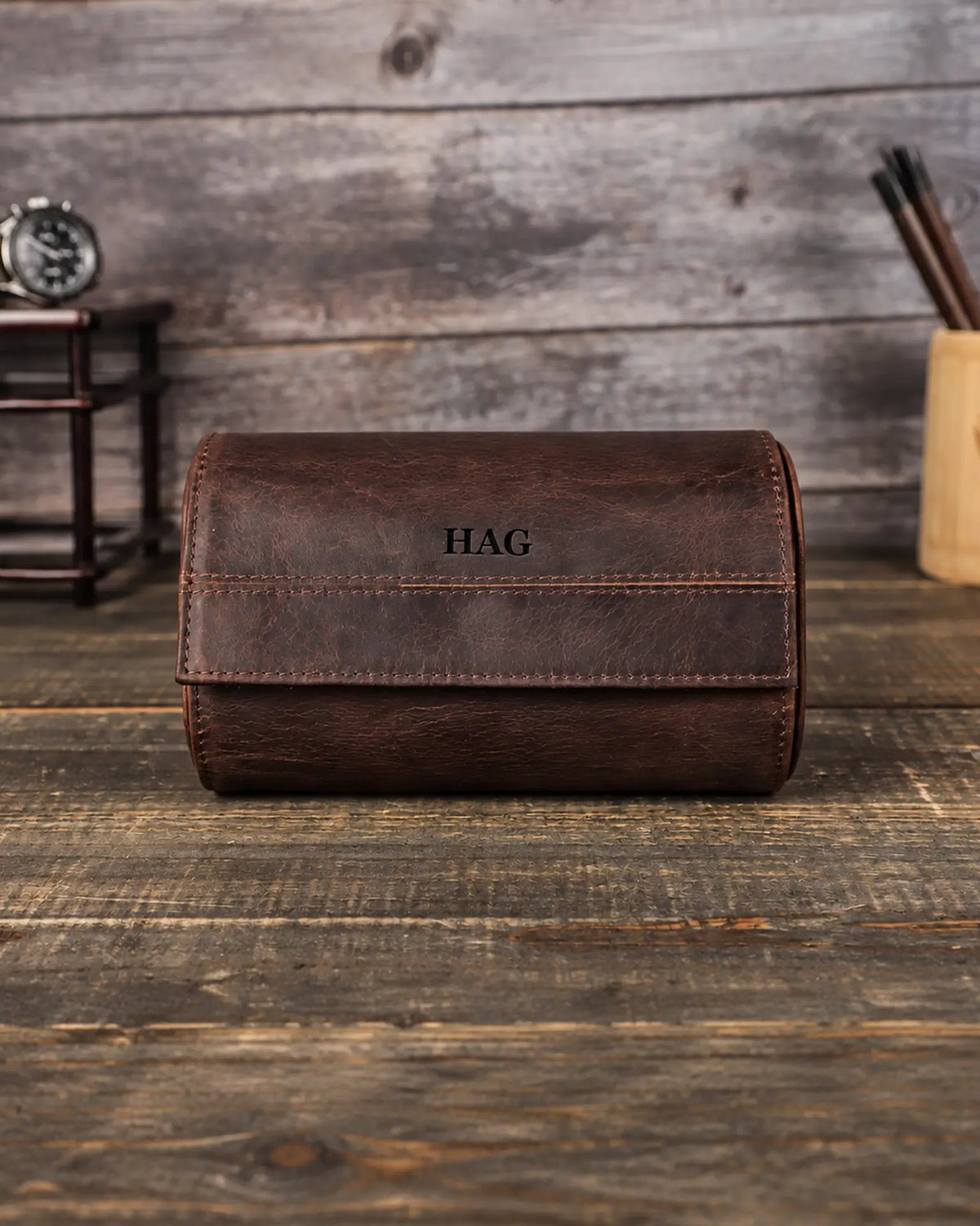 Front view of a brown double watch roll with an HAG monogram centered on the flap. Personalization example.