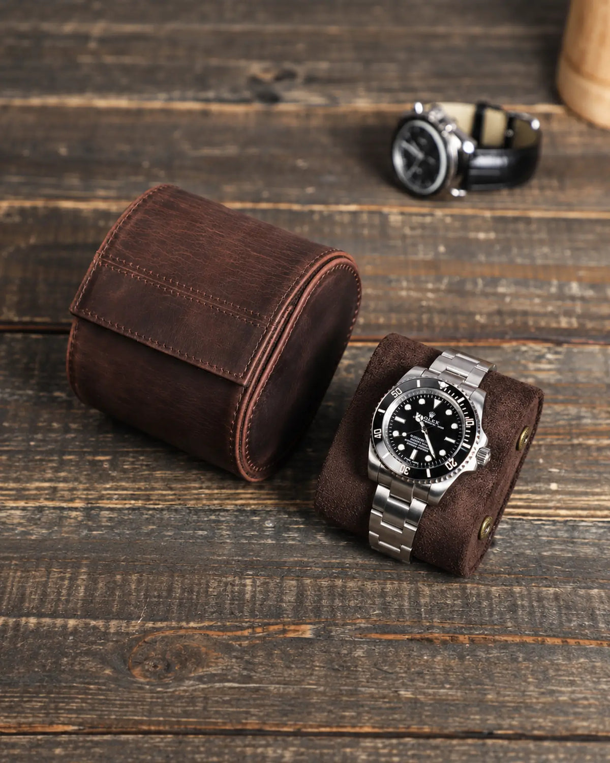 Espresso watch roll with its removable cushion and a metal-bracelet watch on a wooden tabletop.