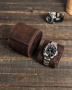 Espresso watch roll with its removable cushion and a metal-bracelet watch on a wooden tabletop.