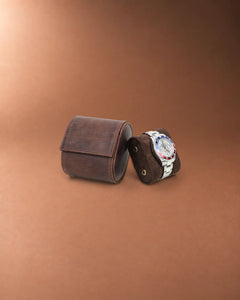 Closed Espresso leather watch roll beside its removable cushion holding a watch.
